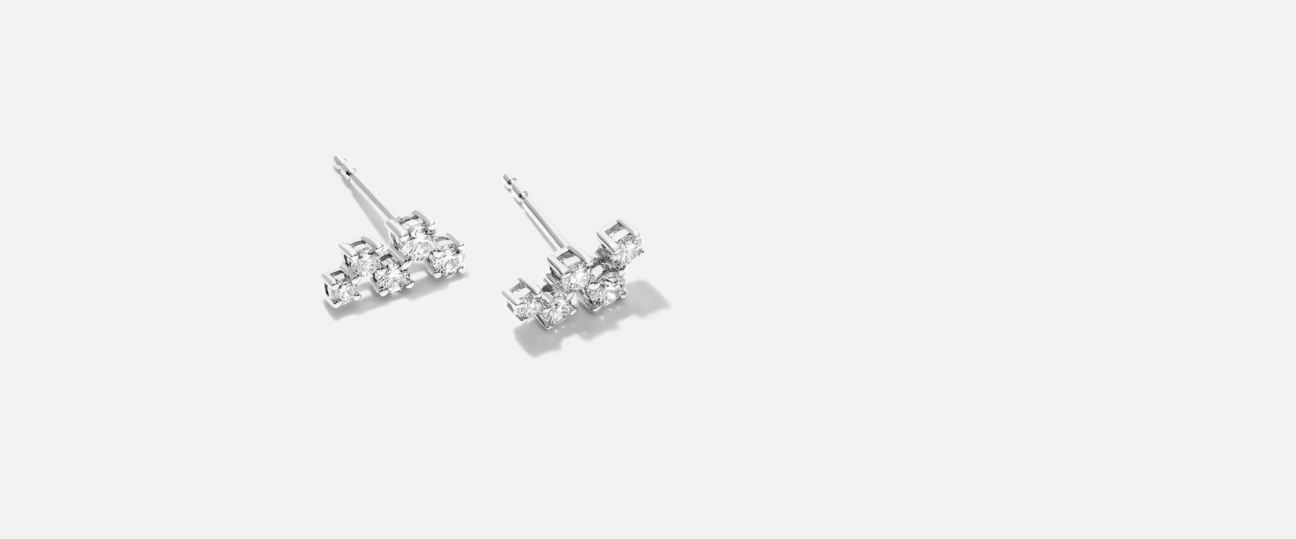 A pair of diamond earrings lay on a white background.