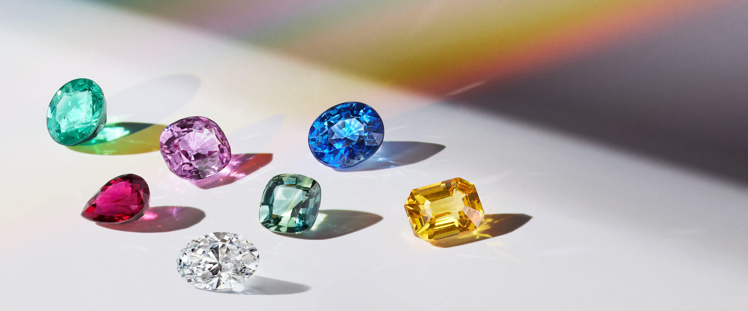 A collection of fancy shaped diamonds and gemstones in various rainbow colors