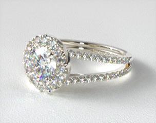 A sparkling halo of pavé-set diamonds encircles the center gemstone of this inspiring split shank beauty.