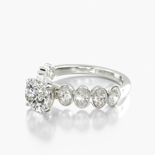 This simple yet unique ring features beautiful oval diamonds within a secure bezel setting that creates a graceful scalloped motif to perfectly compliment the center diamond of your choice