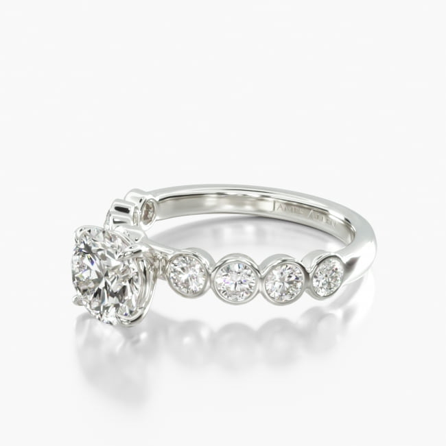 This simple yet unique ring features beautiful round diamonds within a secure bezel setting that creates a graceful scalloped motif to perfectly compliment the center diamond of your choice
